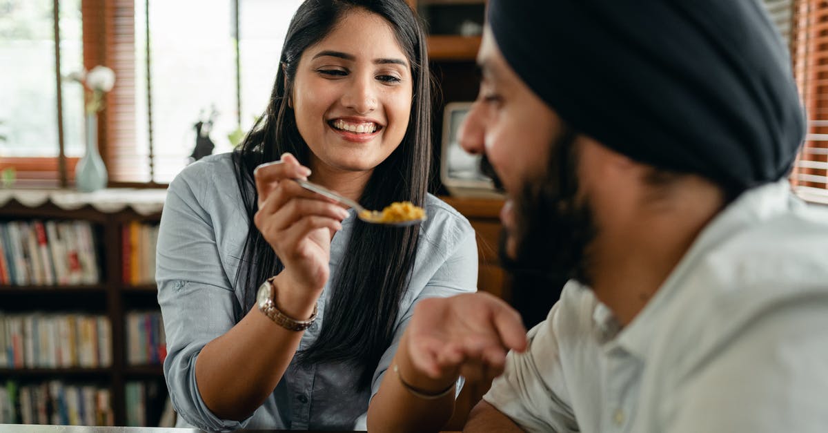 Why is the chicken in Indian food so tender? - Positive young ethnic lady feeding boyfriend with delicious food Why is the chicken in Indian food so tender? - Positive young ethnic lady feeding boyfriend with delicious food