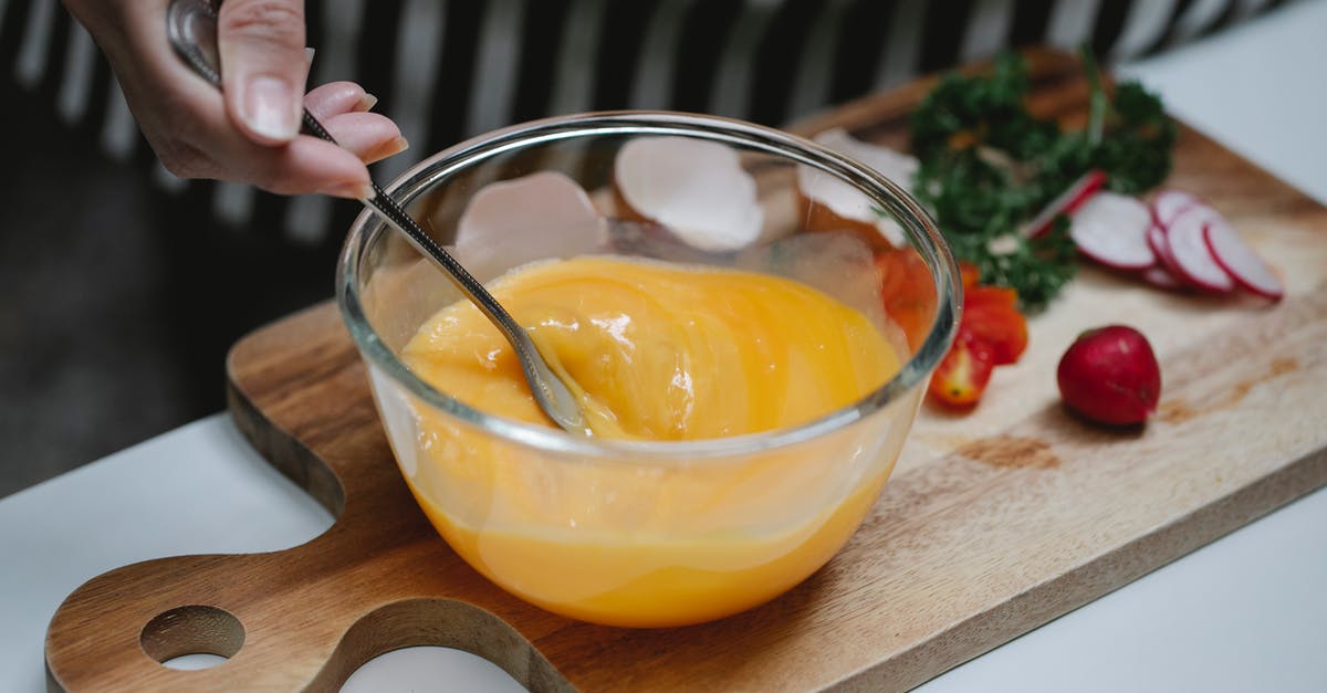 Why or why not beat an egg before adding? - High angle of crop female beating eggs in glass bowl standing at table with ingredients for breakfast on cutting board Why or why not beat an egg before adding? - High angle of crop female beating eggs in glass bowl standing at table with ingredients for breakfast on cutting board