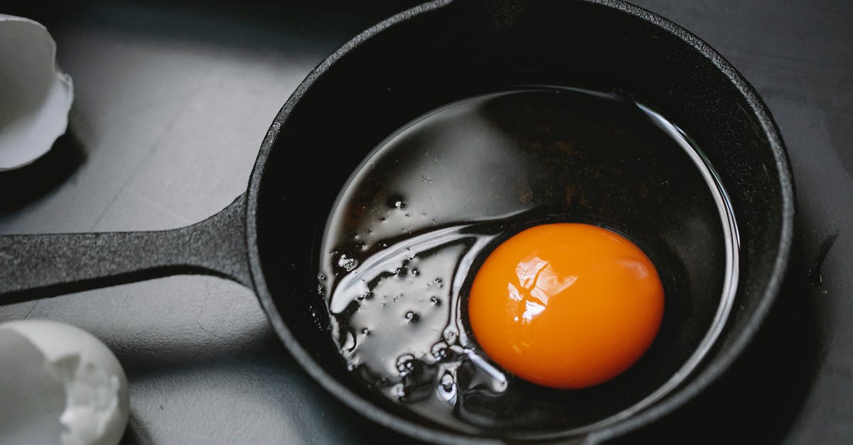 Why reoil a cast-iron pan after usage? - From above of frying pan with uncooked egg yolk and white placed on table near scattered shells in kitchen Why reoil a cast-iron pan after usage? - From above of frying pan with uncooked egg yolk and white placed on table near scattered shells in kitchen