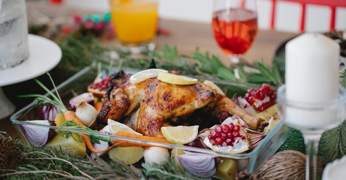 Why season the meat "liberally"? - Roasted chicken on glass form with lemons and pomegranate and carrots on festive decorated table for Christmas celebration with cocktails and candles Why season the meat "liberally"? - Roasted chicken on glass form with lemons and pomegranate and carrots on festive decorated table for Christmas celebration with cocktails and candles