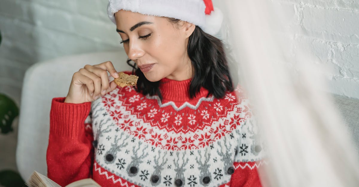 Why should I rest gingerbread dough? - Young female in warm Christmas sweater and hat sitting on sofa while reading interesting book and having gingerbread Why should I rest gingerbread dough? - Young female in warm Christmas sweater and hat sitting on sofa while reading interesting book and having gingerbread
