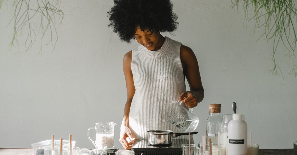 Why should we add alcohol to make extract - Positive African American female artisan pouring liquid in pot while making wax for candles in pot on cooker Why should we add alcohol to make extract - Positive African American female artisan pouring liquid in pot while making wax for candles in pot on cooker