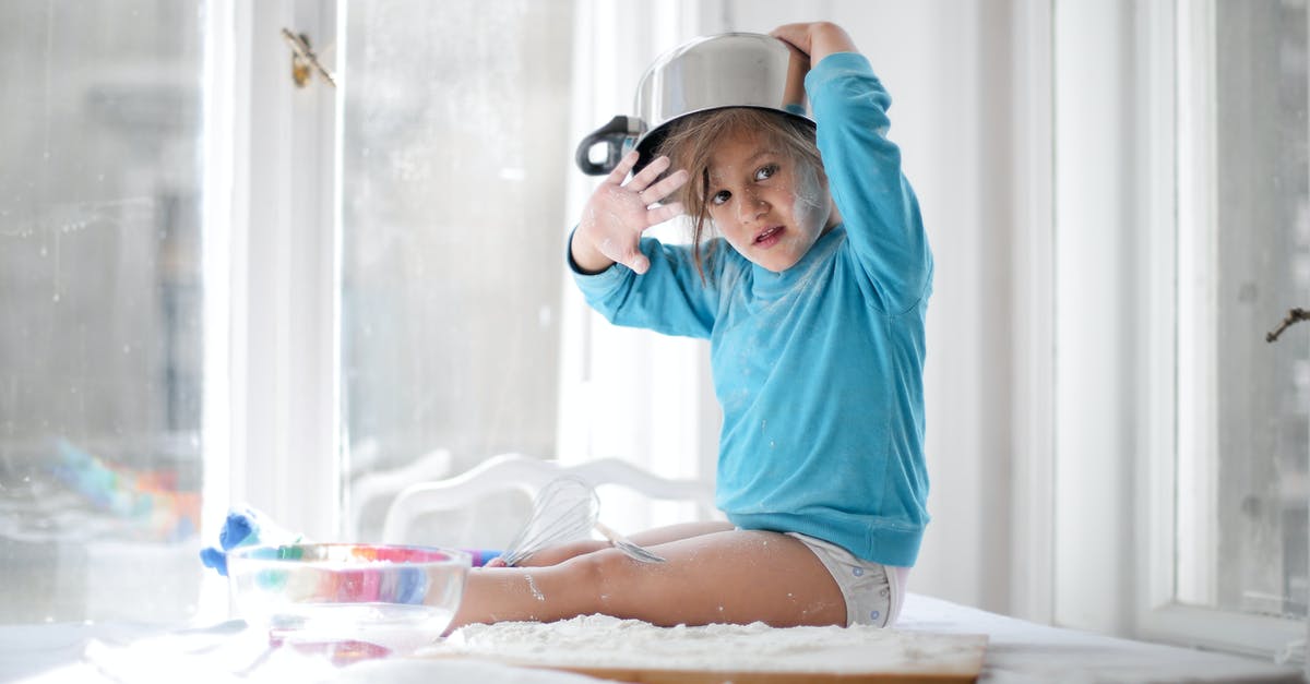 Why use metal cake pan instead of silicone one? - Little girl playing with pan and flour in kitchen Why use metal cake pan instead of silicone one? - Little girl playing with pan and flour in kitchen
