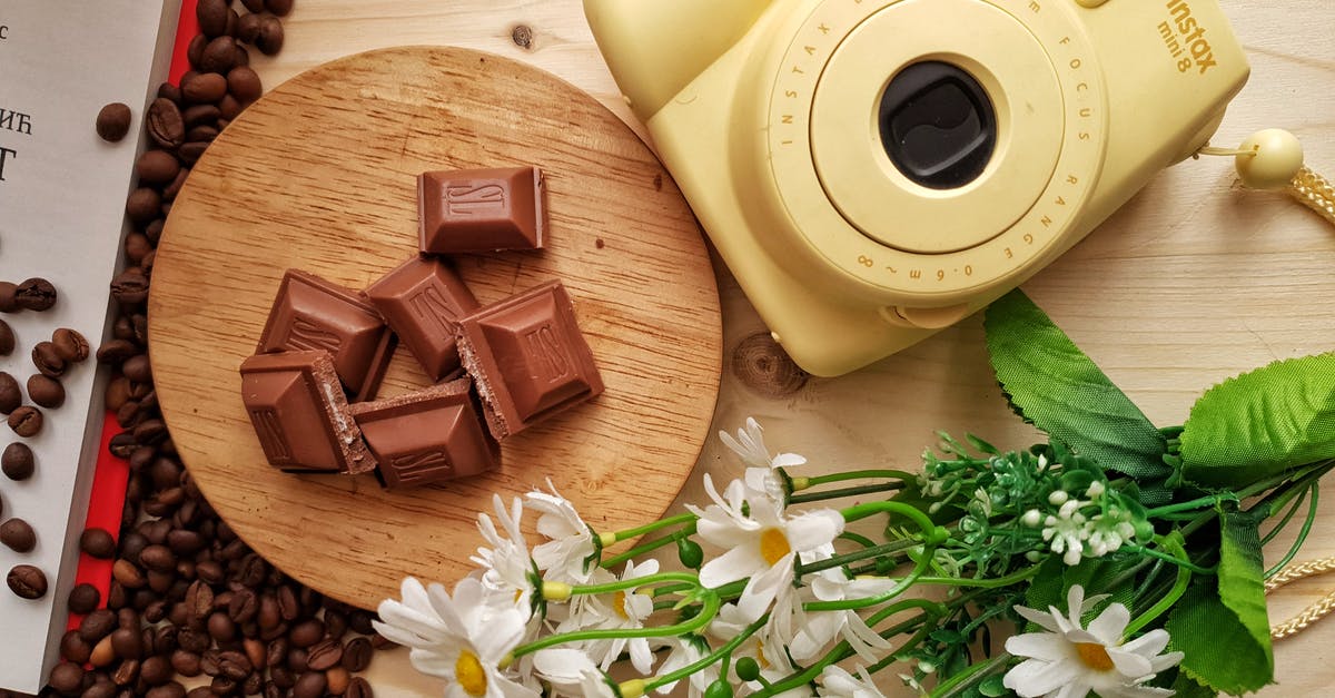 Why use milk in scrambled eggs? - Top view of delicious pieces of milk chocolate bar with filling on wooden board near heap of aromatic coffee beans and instant camera with artificial chamomiles on table