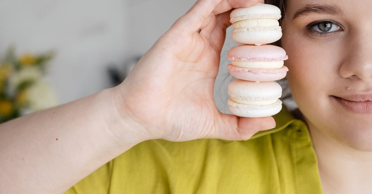 Will colored shredded coconut show up in brownies? - Crop female holding yummy macaroons in hand near face on blurred background and looking at camera Will colored shredded coconut show up in brownies? - Crop female holding yummy macaroons in hand near face on blurred background and looking at camera
