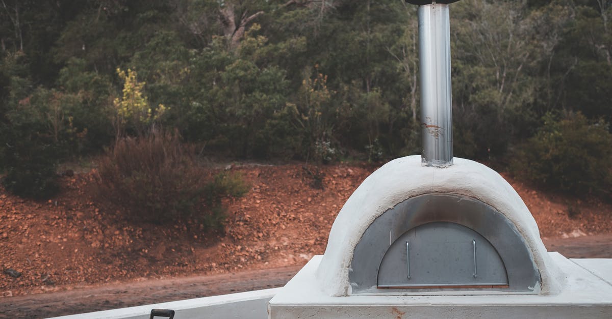 Will seasoning stainless steel increase heat transfer to pizza dough? - Stone pizza oven with stainless flue placed in lush summer garden for picnic