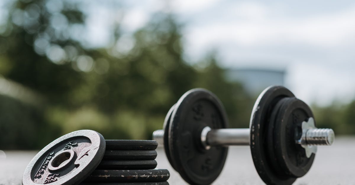 Wok: Carbon steel or cast iron? - Dumbbell with heap of plates on asphalt road