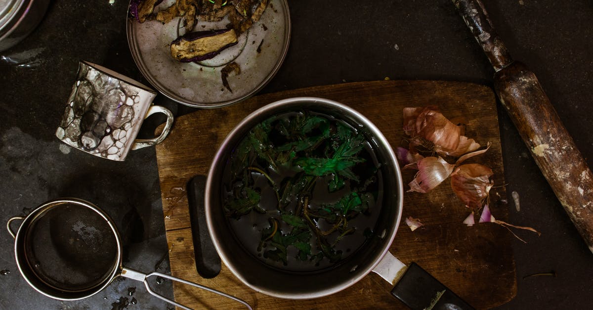 Wooden cooking layout - Top view of metal saucepan with broccoli on cutting board with onion near sieve and dirty mug Wooden cooking layout - Top view of metal saucepan with broccoli on cutting board with onion near sieve and dirty mug