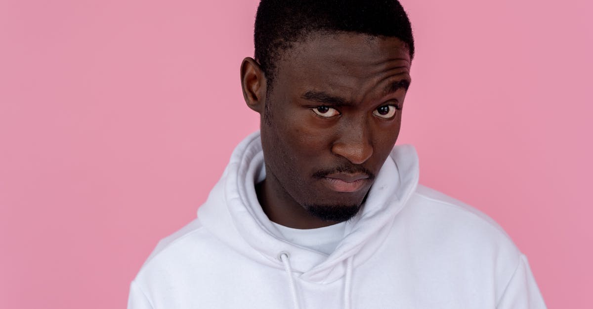 Yeast amounts unsure - Serious African American male model wearing white sweatshirt looking at camera with unsure gaze against pink background Yeast amounts unsure - Serious African American male model wearing white sweatshirt looking at camera with unsure gaze against pink background
