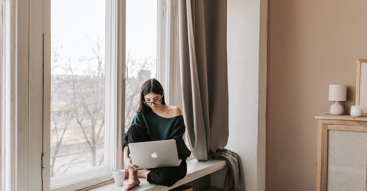 Yolks flat and breaking - Young female freelancer sitting with laptop on windowsill at home Yolks flat and breaking - Young female freelancer sitting with laptop on windowsill at home